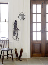 Load image into Gallery viewer, 10&quot; English leather-framed equestrian mirror hanging on a wall with tack accessories nearby.