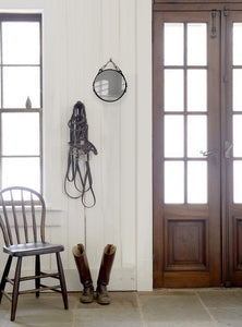 10" English leather-framed equestrian mirror hanging on a wall with tack accessories nearby.